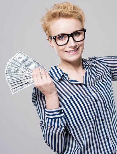 a smiling woman with short blonde hair and glasses, wearing a striped shirt, holding a fan of dollar bills in her hand against a gray background, representing
