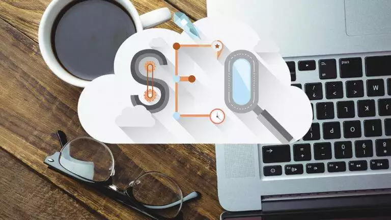 top down view of a desk with a laptop, coffee cup, and glasses, overlaid with graphics of clouds, a dollar sign, and magnifying glasses symbolizing cloud computing and profitable financial analysis.