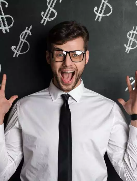 A joyful man in a white shirt and black tie, wearing glasses, excitedly raises his hands against a chalkboard background with dollar signs drawn on it, celebrating his success in doubling their online income.
